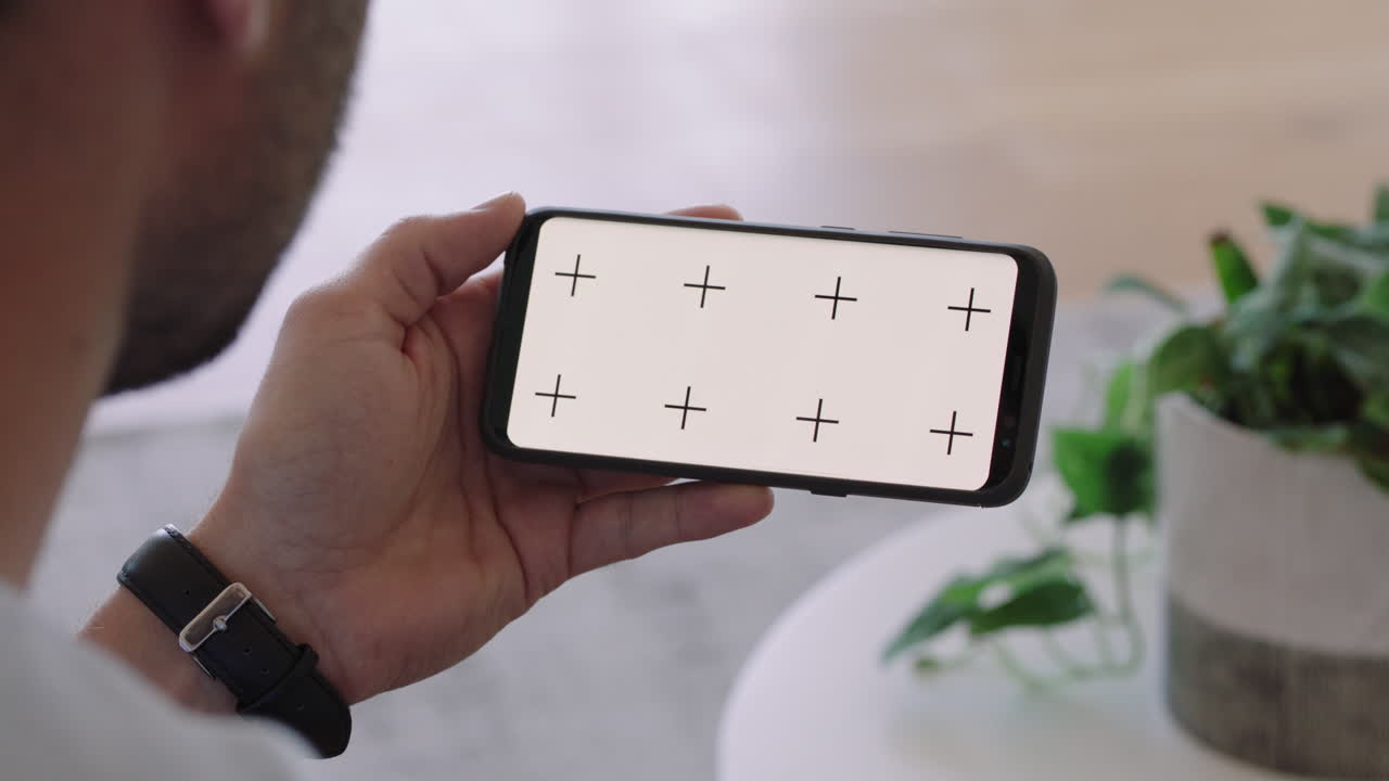 스마트폰을 사용하는 젊은 남자가 녹색 화면을 보고 크로마 키를 보고 휴대폰에서 온라인 엔터테인먼트를 즐기고 있다