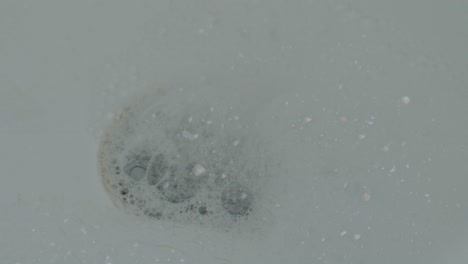 draining foam and water in drain hole of wash basin - close up