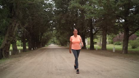 the lady is walking briskly in the park - wide shot