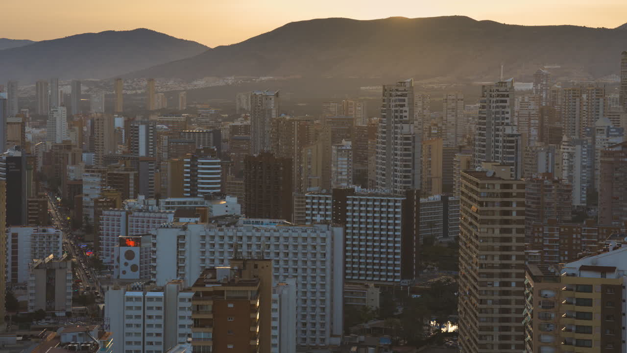inclinación aérea hacia abajo para revelar el paisaje urbano de benidorm con rascacielos al atardecer
