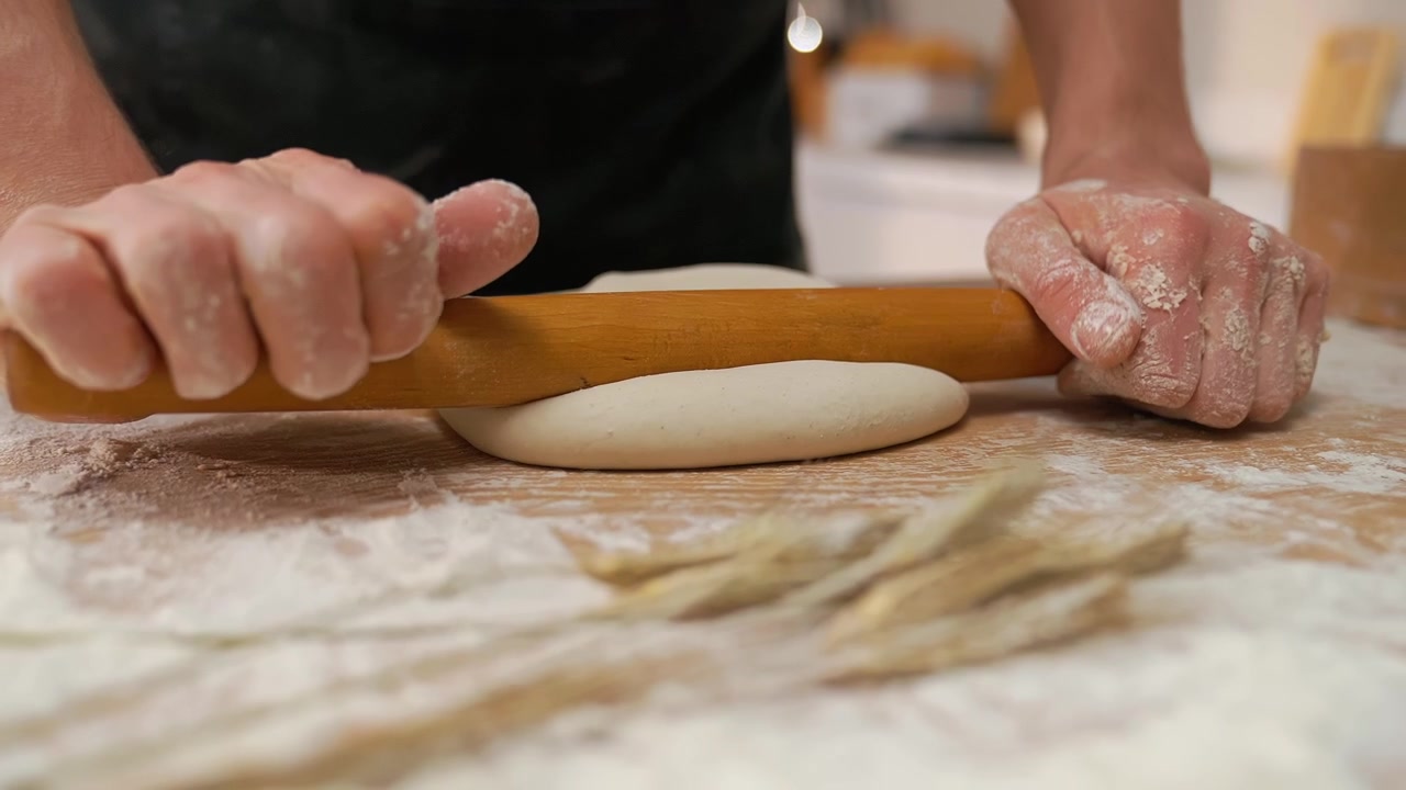 Close-up of Hands Rolling Dough with a Wooden Rolling Pin