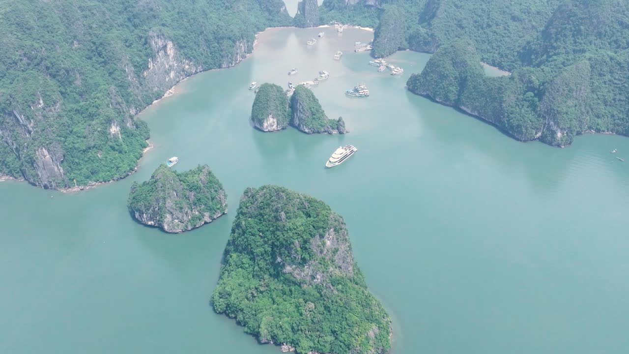 Lush green limestone mountains and river boats in Ha Long Bay, Vietnam from above