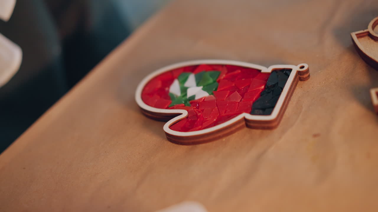Red mitten ornament on wooden table festive christmas decoration styled as gift tag holly detail shallow depth of field warm cozy lighting macro closeup handcrafted holiday craft