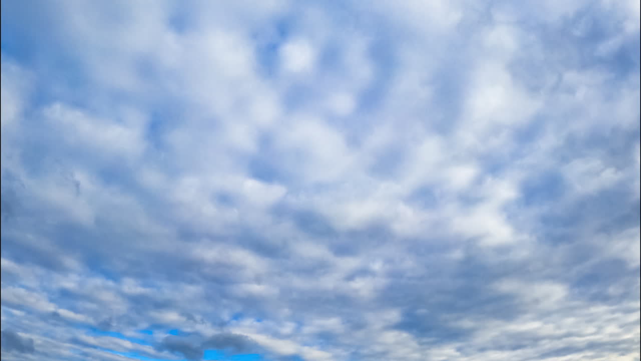Overcast sky at daytime. Low angle view on the grey cloudscape spread by the horizon.
