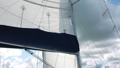 a panning shot of sails of a sailing yacht in the wind on blue summer sky in the morning time