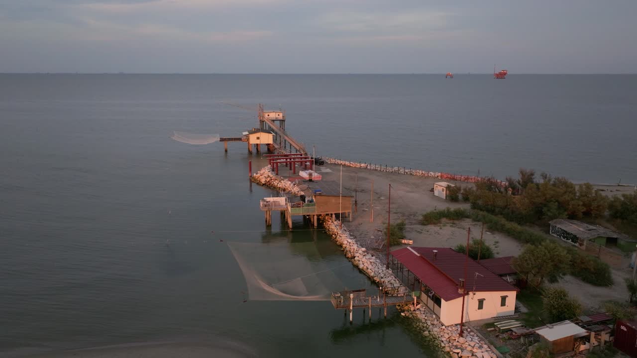 vista aérea de cabañas de pesca a orillas del estuario al atardecer, máquina de pesca italiana, llamada "trabucco", lido di dante, ravenna cerca del valle de comacchio