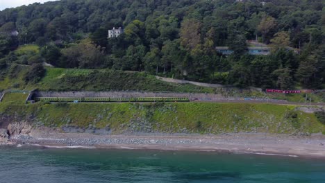 aerial shot of a train riding by the irish coastline in ireland