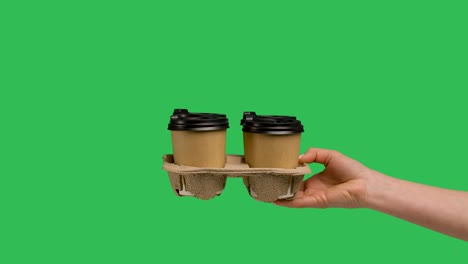 la mano femenina da un conjunto de tazas de papel con café o té caliente. primer plano de tazas de papel con café de barista aislado en pantalla verde llave de croma. concepto de servicio de entrega de alimentos y bebidas. cámara lenta