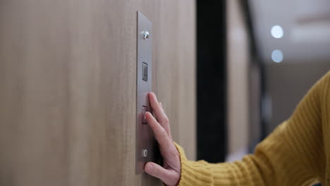 close up of a hand pressing an elevator button