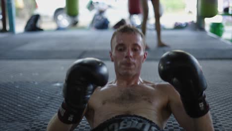 man doing crunches with boxing gloves during training