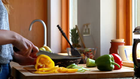 Mujer-Joven-Cortando-Pimientos-Junto-A-La-Ventana