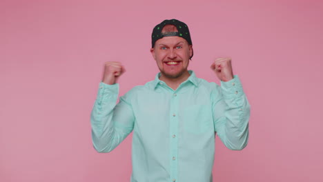 stylish man in shirt shouting, raising fists in gesture i did it, celebrating success, winning