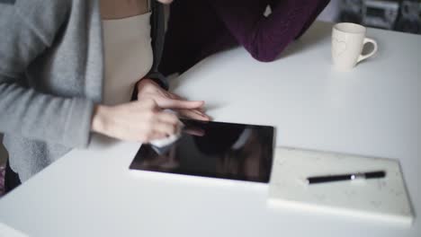 manos femeninas limpiando la superficie de la pantalla de la tableta con un paño tendido en la mesa