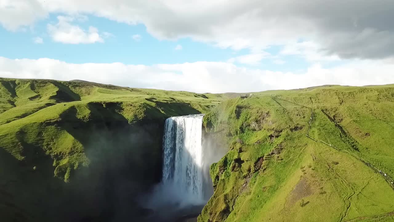 una toma de avance de la cascada de skogafoss en islandia con gaviotas volando a su alrededor al atardecer