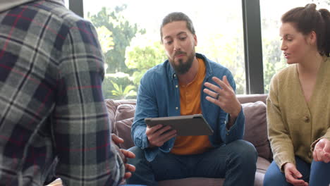 Heterogene-Gruppe-Von-Freunden-Und-Männlicher-Therapeut-Mit-Tablet-In-Gruppentherapiesitzung