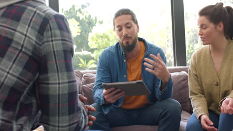 diverse group of friends and male therapist with tablet in group therapy session