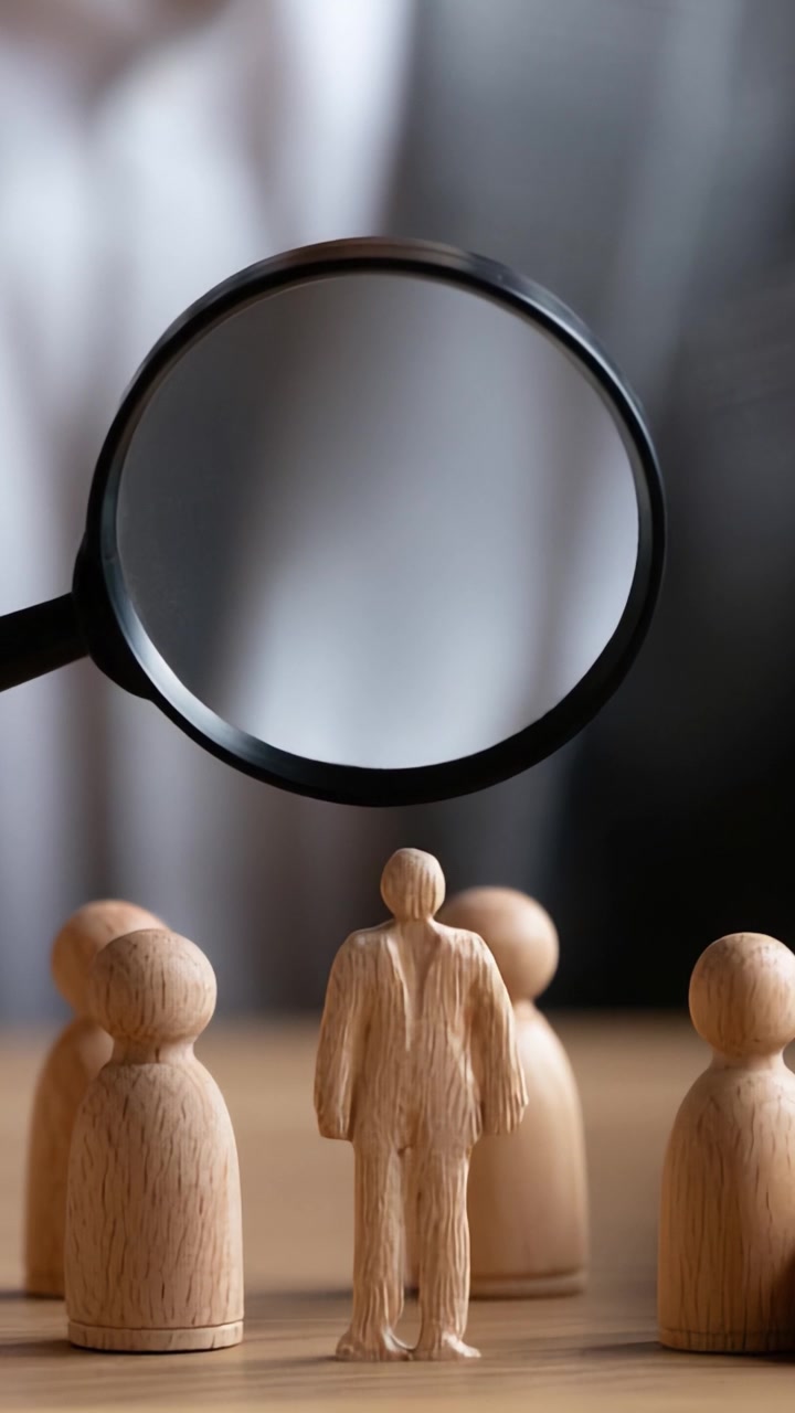 Esame dell'individualità: una prospettiva focalizzata su figure di legno sotto ingrandimento in un contesto di gruppo.
