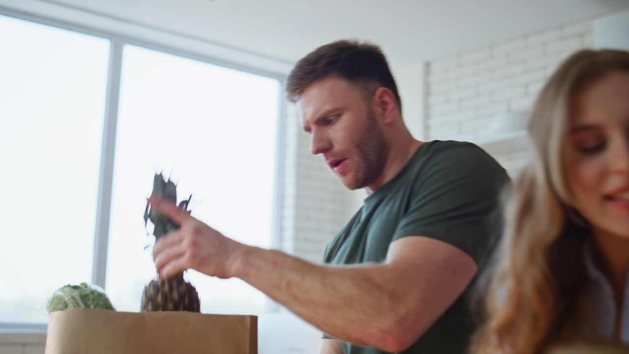 Happy pair carrying bags in kitchen closeup. Couple unpacking food groceries