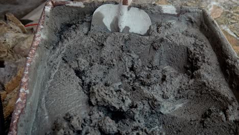 pull shot reveals builders rusty wheelbarrow full of wet mixed cement