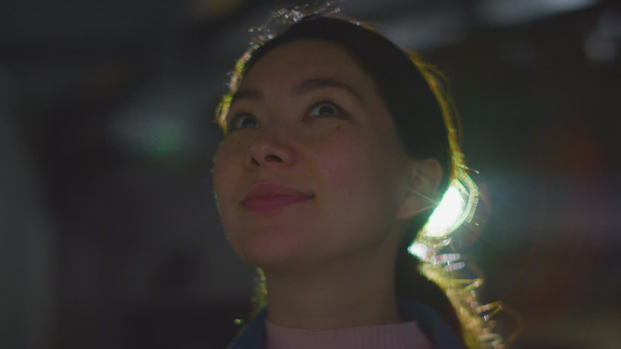 프로젝터 5의 빛으로 백라이트 된 몰입 예술 전시회를 방문하고 상호 작용하는 여성의 클로즈업