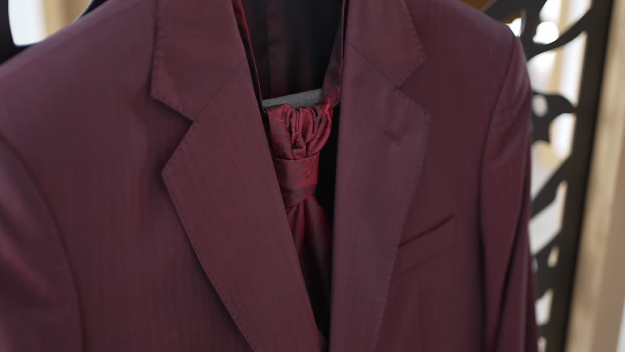어리에 매달린 은 타이와 함께 우아한 버곤디색 슈트 재의 클로즈업