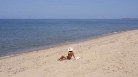 mujer joven en bikini sentada en una playa de arena