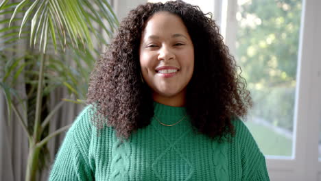 Portrait-of-happy-african-american-woman-with-long-curly-hair-smiling-by-sunny-window,-slow-motion