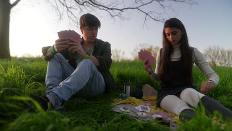 couple playing cards in a park at sunset