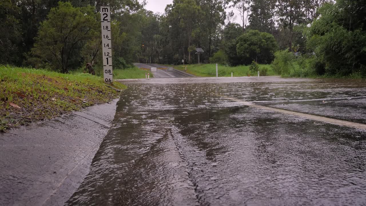 gold coast, queensland, 16 de febrero de 2024 - bajo golpe de flujo de agua en inundaciones a través de la carretera de hardy en mudgeeraba después de que las fuertes lluvias continúan azotando el sureste de queensland, australia