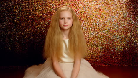 portrait of a young girl in an elegant dress against a sparkly golden background