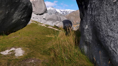 Trucking-shot-of-gigantic-rocks-and-snowy-mountains-in-background-on-castle-hill-national-park-in-New-Zealand