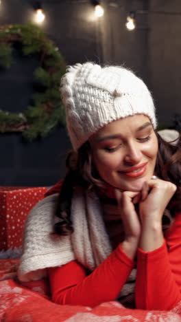 portrait of a beautiful woman on bed. smiling young female having fun at home on christmas tree background. positive girl looking at camera at new year. vertical video