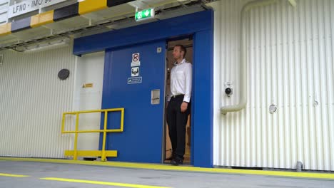 ferryboats sliding door opening and ships captain coming out from entrance - low angle static seen from car deck area