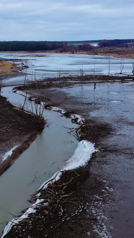 Dirty river in spring. Disaster ecology in nature. Dark background of fields and river in rural place. Environmental problems. Vertical video