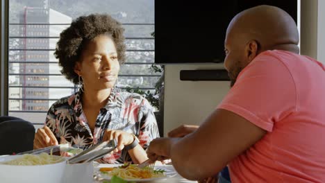 Father-teaching-his-son-eating-with-fork-and-knife-at-dining-table-4k