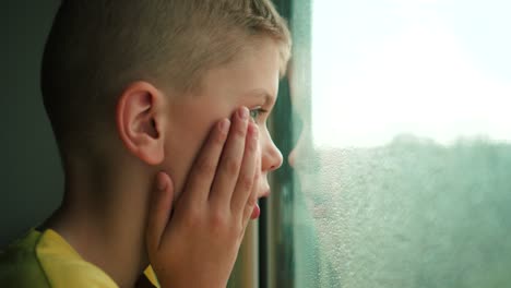 Niño-Mirando-La-Lluvia-A-Través-De-Una-Ventana