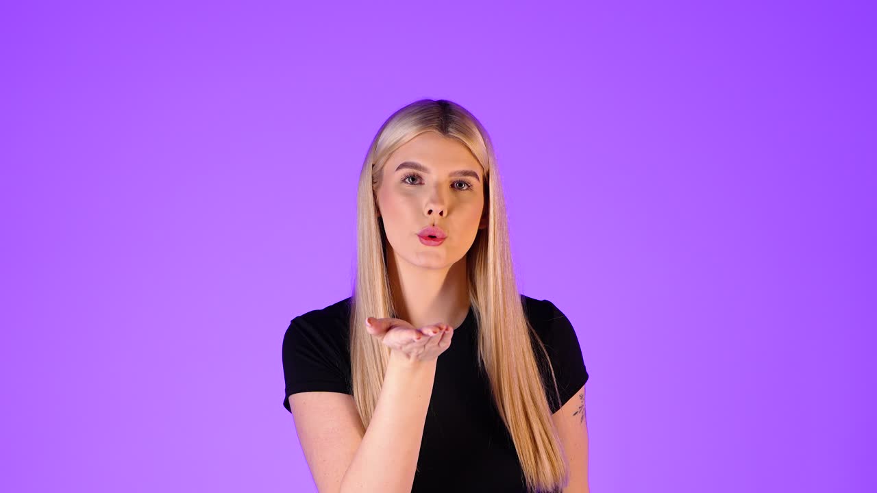 Attractive Blonde Woman Blowing a Kiss Towards Camera, Colorful Studio Portrait