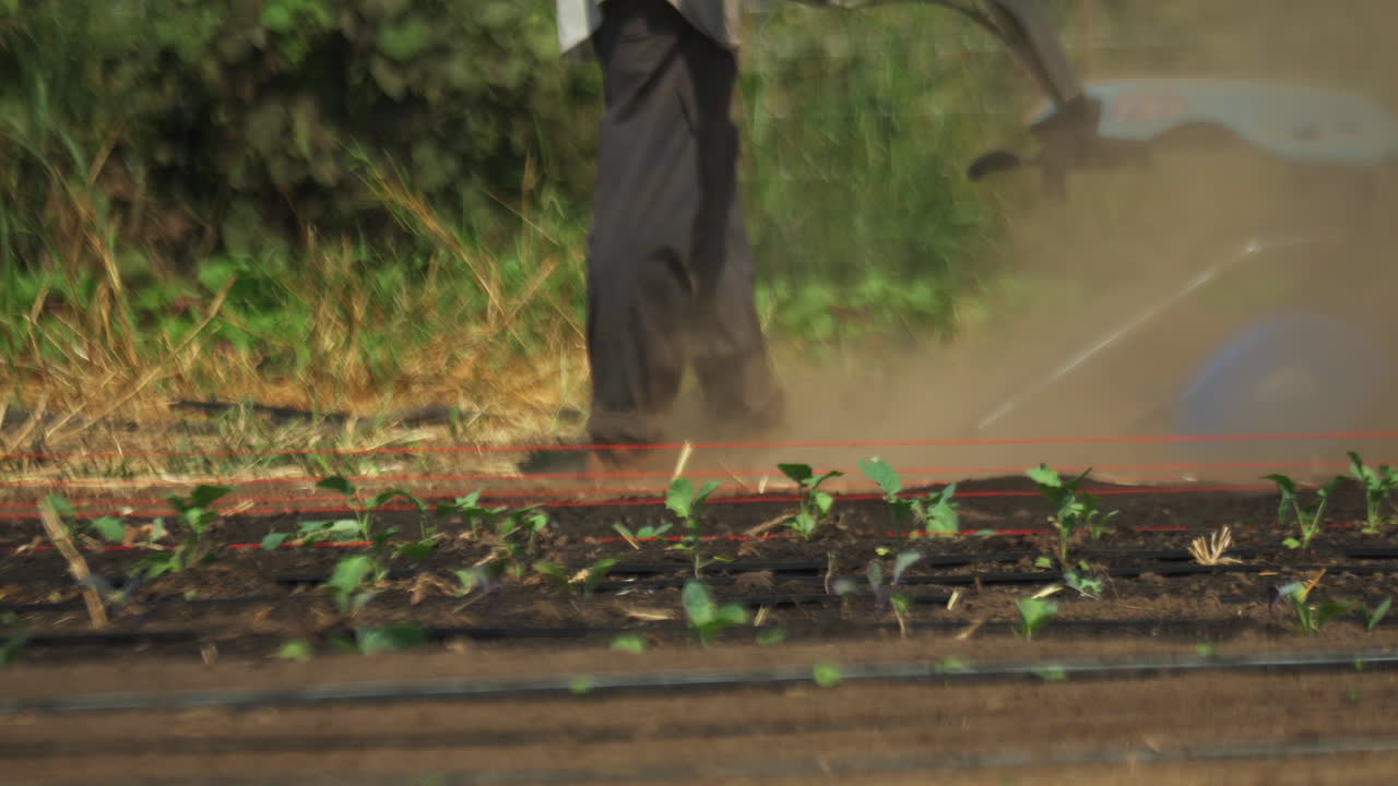 Primo piano di un contadino che lavora il terreno agricolo con una motozappa a motore.