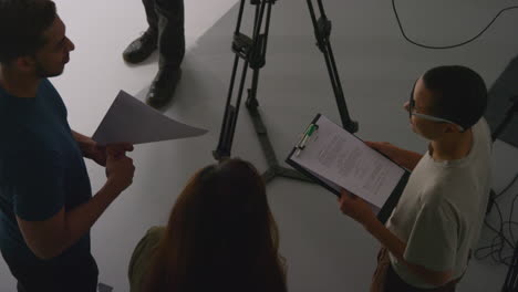 fotografía aérea del director de cine hablando con actores masculinos y femeninos sosteniendo guiones ensayando para filmar una película o un video en el estudio