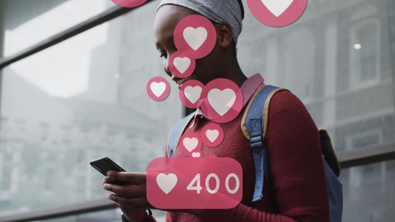 animación de los iconos del corazón de las redes sociales sobre una mujer afroamericana sonriente que usa un teléfono inteligente en la calle