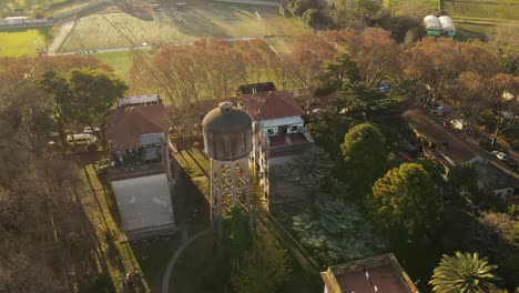 Aerial-view-orbiting-an-old-water-tank-located-in-the-vicinity-of-several-multi-storey-buildings