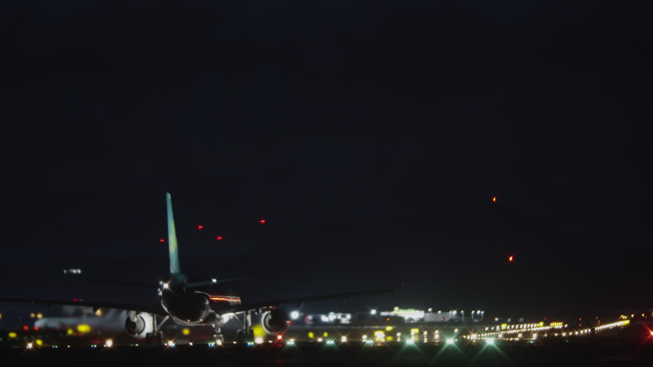 ピッチブラックな夜空に対して滑走路を移動する飛行機
