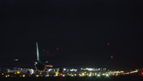 a plane moving on a runway against the pitch black night sky