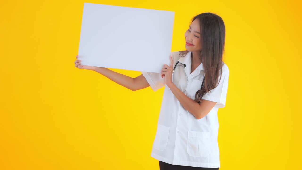 Asian doctor nurse holding a blank sheet of the paper poster banner in hands with a happy face expression