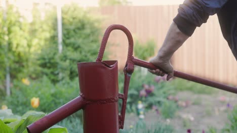 hombre caucásico bombeando agua con una bomba de agua manual