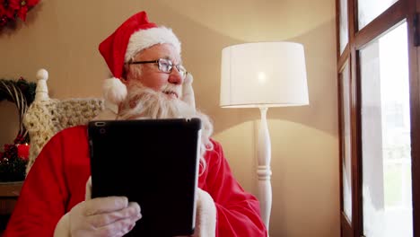 santa claus looking through window while using digital tablet