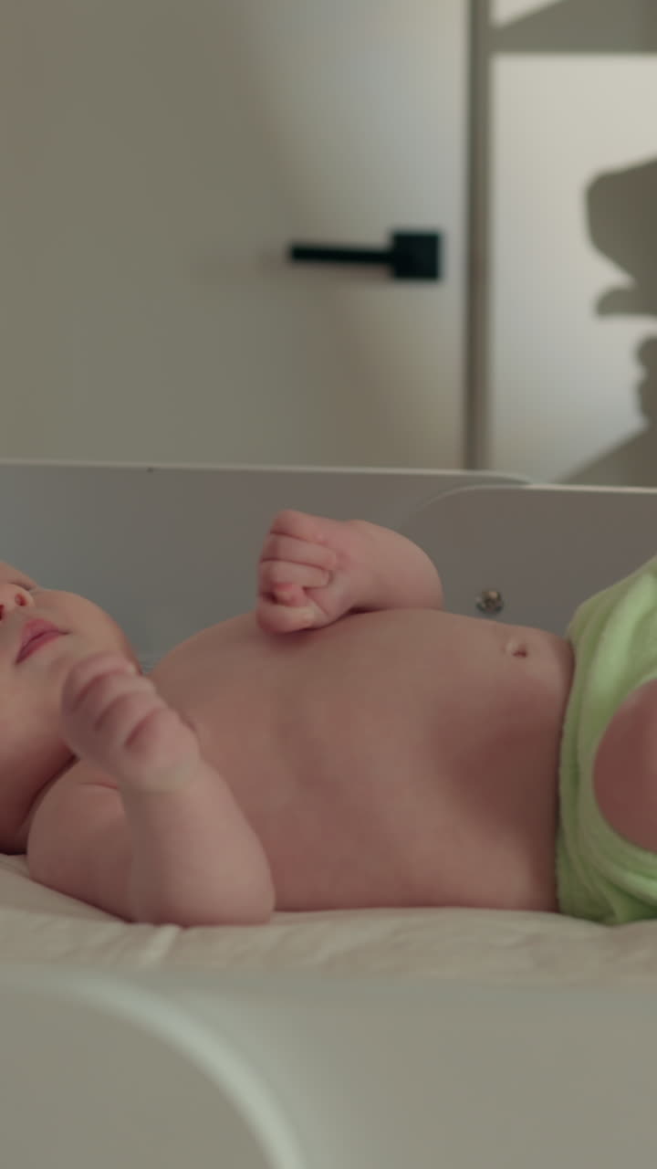 Primo piano di un neonato sereno che dorme profondamente in una culla, mostrando lineamenti delicati e piccoli dettagli