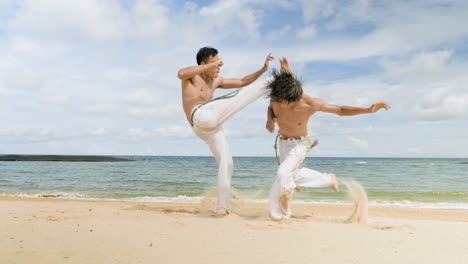 two men dancing capoeira on the beach