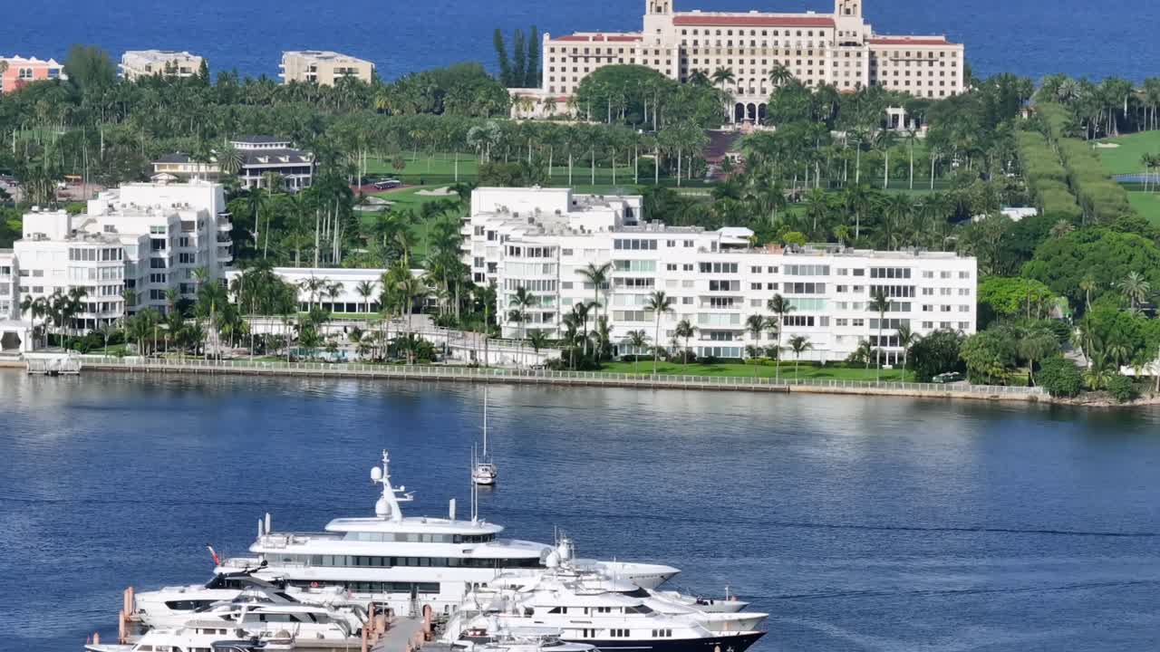 Aerial view of a luxurious oceanfront resort with a golf course, residential buildings, and boats on the water