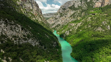 Aerial-flying-forward-over-Verdon-Gorge-on-sunny-day,-boats-sailing,-France